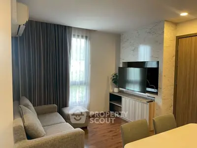 Modern living room with stylish decor and natural light, featuring a cozy sofa and sleek entertainment unit.