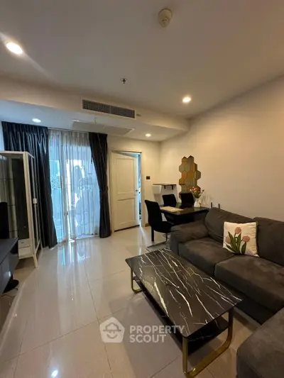Modern living room with sleek black marble coffee table and stylish gray sofa, featuring elegant decor and ample natural light.