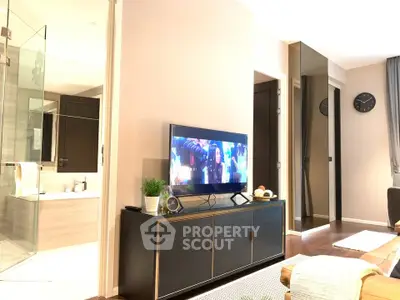 Modern living room with TV and stylish decor, adjacent to a luxurious bathroom.