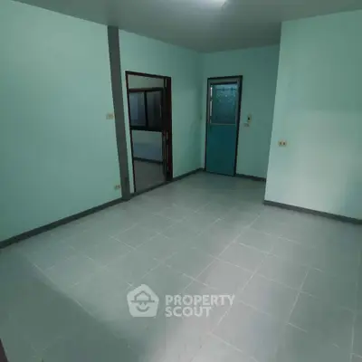 Spacious empty room with tiled floor and teal accents