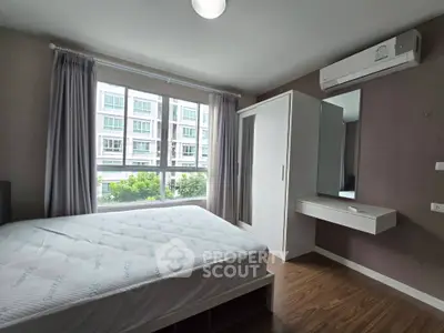 Modern bedroom with large window and built-in wardrobe in a stylish apartment.