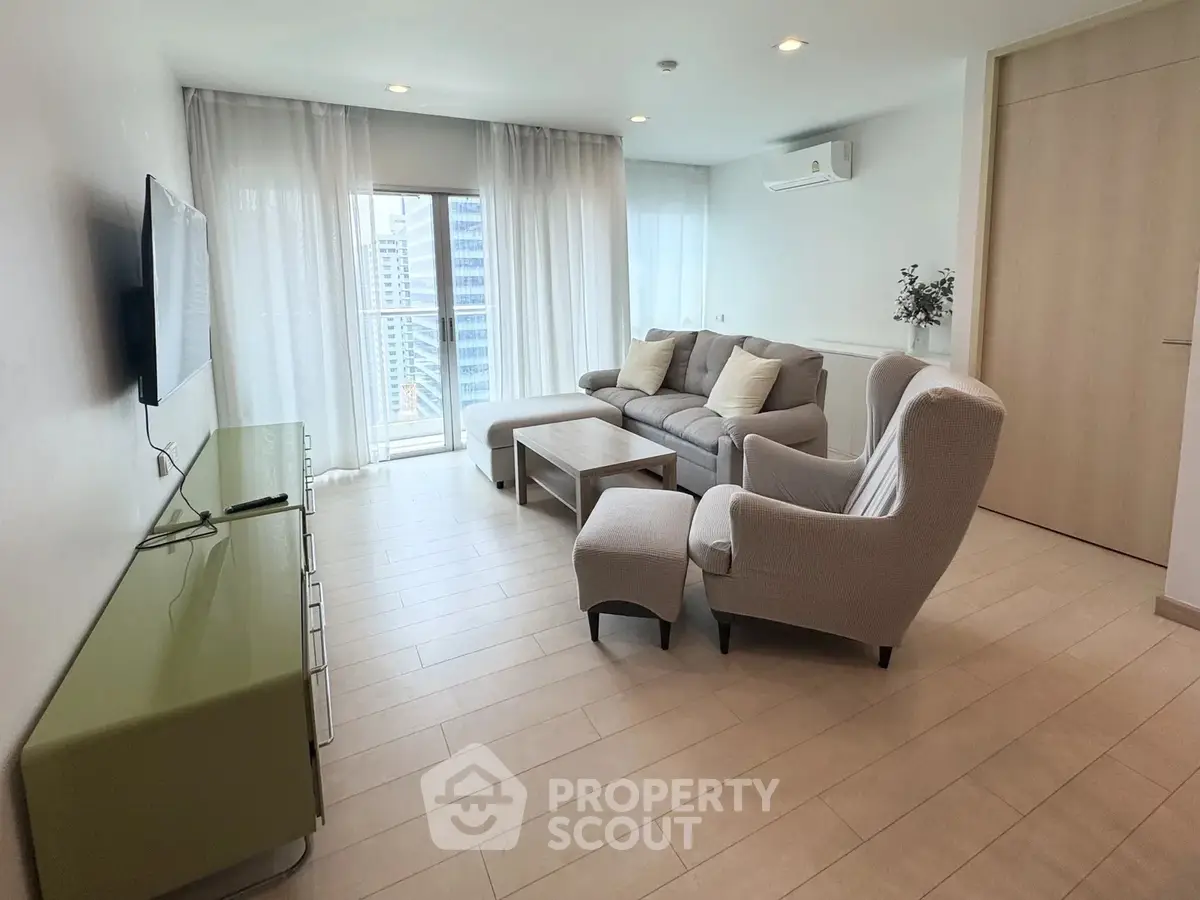 Modern living room with stylish furniture and large window offering city views.