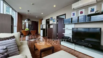Modern living room with sleek furniture and open dining area, featuring wooden flooring and stylish decor.
