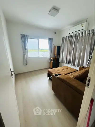 Cozy living room with large window and brown sectional sofa, featuring modern air conditioning.