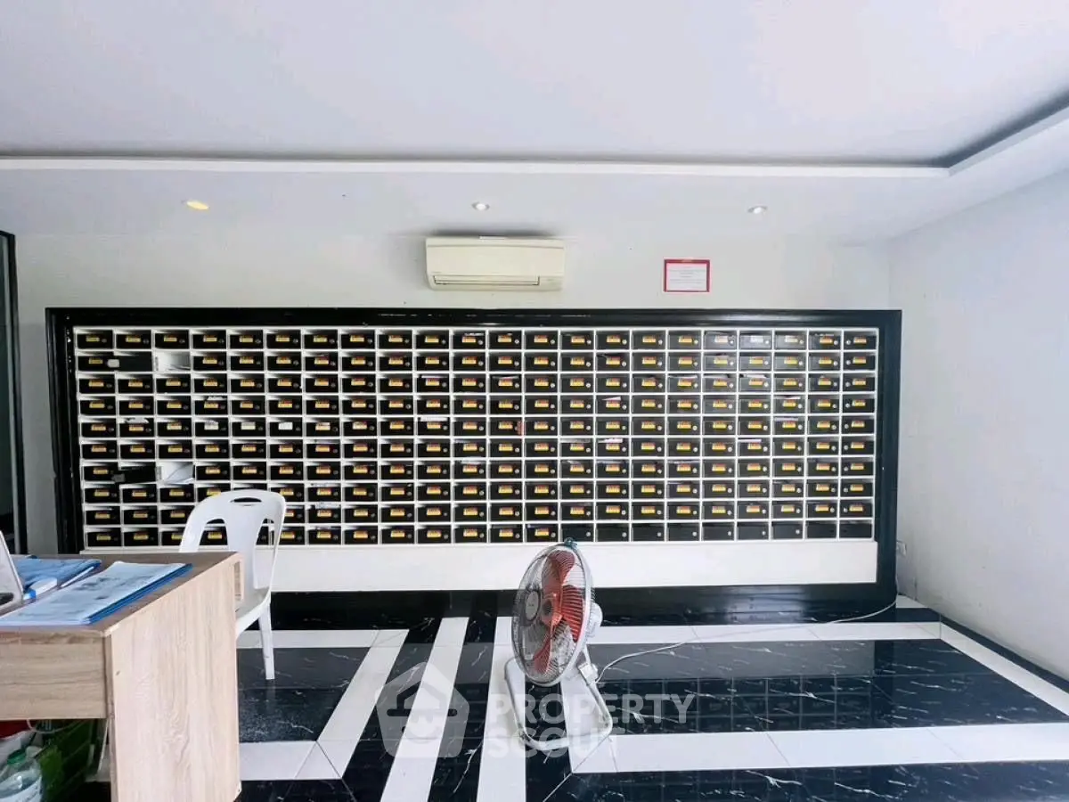 Modern apartment lobby with stylish black and white flooring and multiple mailboxes.
