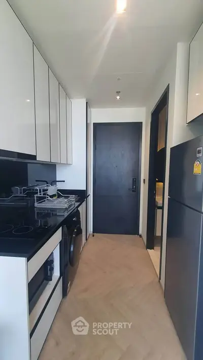 Modern kitchen with sleek black and white cabinetry, gas stove, and appliances in a compact layout.