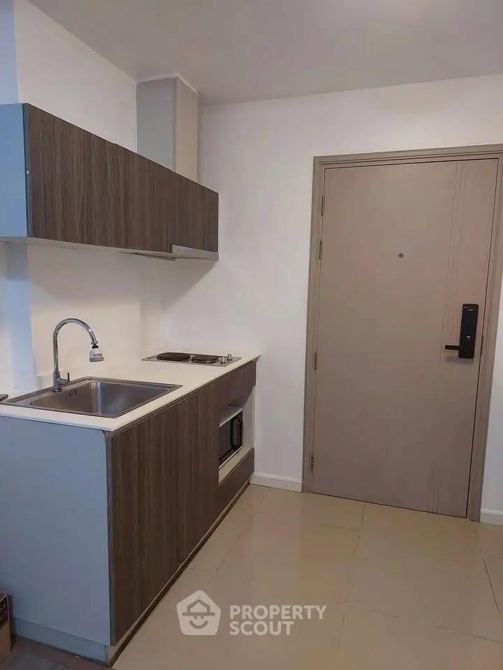 Modern compact kitchen with sleek cabinetry and built-in appliances in a stylish apartment.