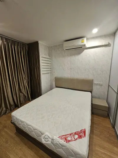 Spacious bedroom with modern decor and air conditioning, featuring a comfortable bed and elegant curtains.
