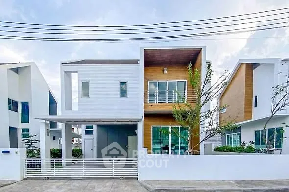 Modern two-story house with sleek design and large windows in a suburban neighborhood.