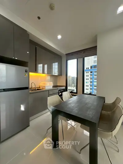 Modern kitchen with sleek cabinets, dining table, and city view from large windows.