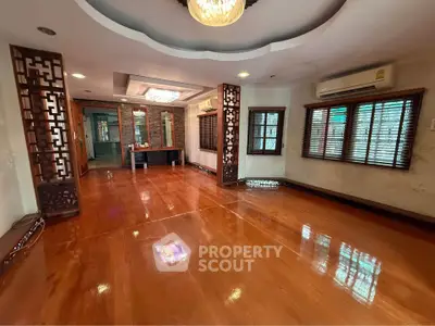 Spacious living room with polished wooden floors and elegant ceiling lights.
