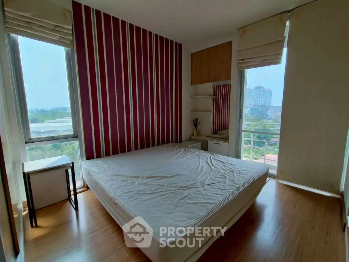 Modern bedroom with large windows and striped accent wall, offering a bright and airy atmosphere.