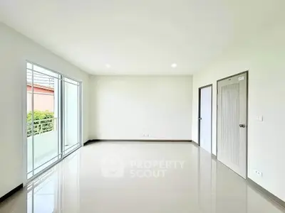 Spacious empty room with large windows and balcony access, perfect for customization.