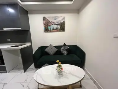 Modern living room with sleek black sofa, stylish decor, and elegant marble flooring.