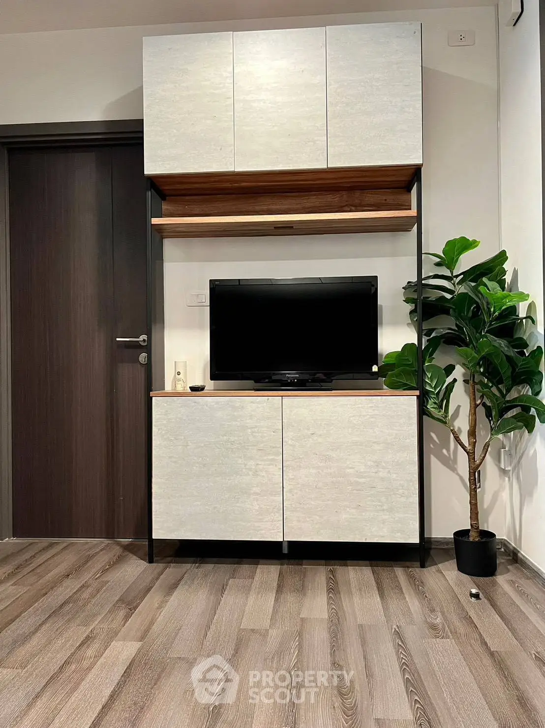 Modern living room with sleek TV cabinet and indoor plant, showcasing stylish interior design.