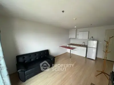 Spacious open-plan living area with sleek hardwood floors, modern kitchen with white cabinetry, and a cozy black sofa, perfect for urban living.