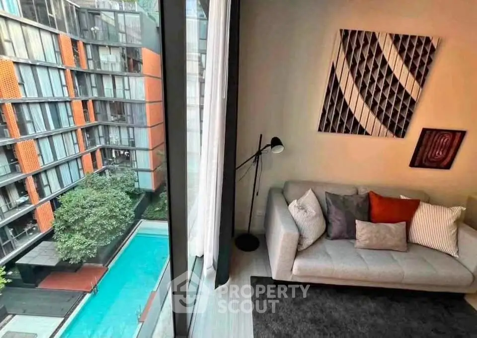 Modern living room with floor-to-ceiling windows overlooking a pool and contemporary building.