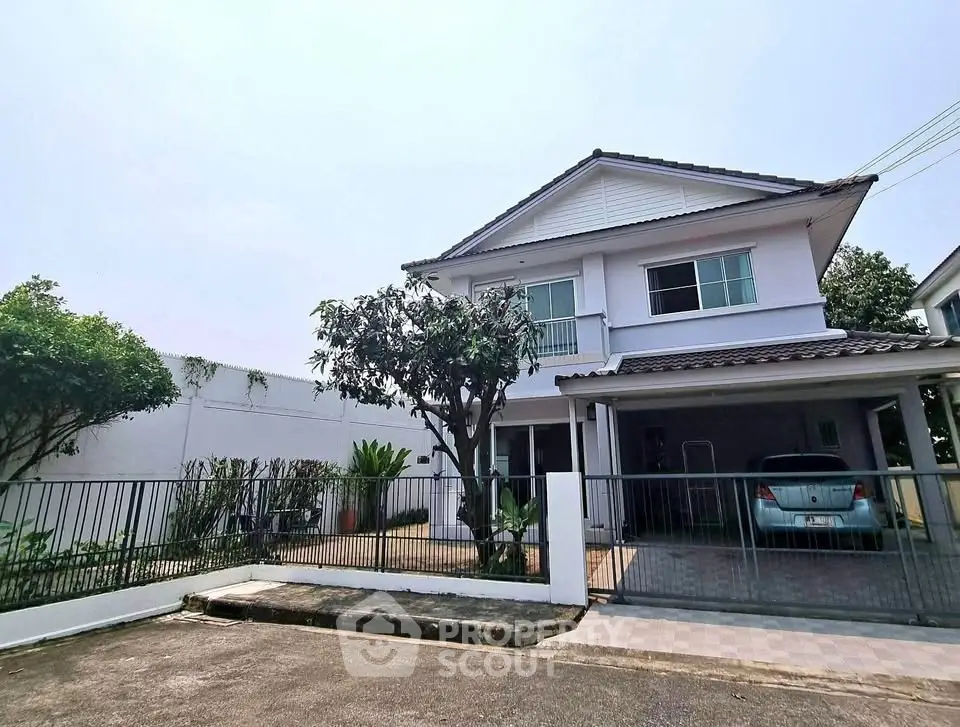 Charming two-story house with carport and lush garden in serene neighborhood.