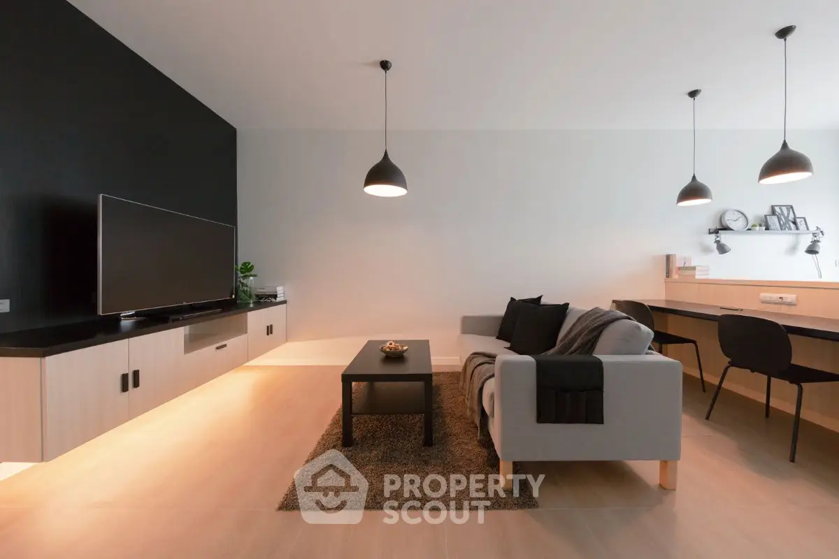 Modern living room with sleek furniture and ambient lighting, featuring a stylish sofa and wall-mounted TV.