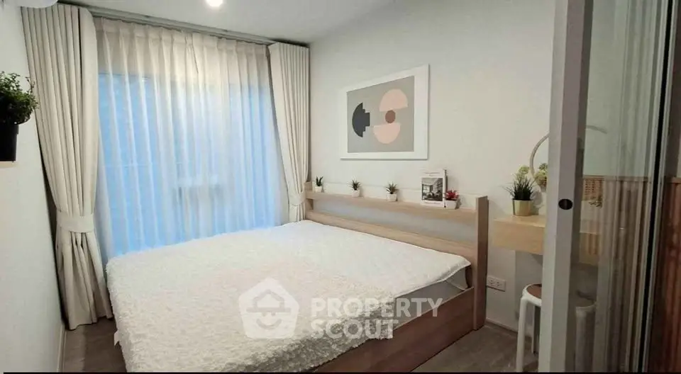Cozy bedroom with modern decor and large window, perfect for relaxation and comfort.
