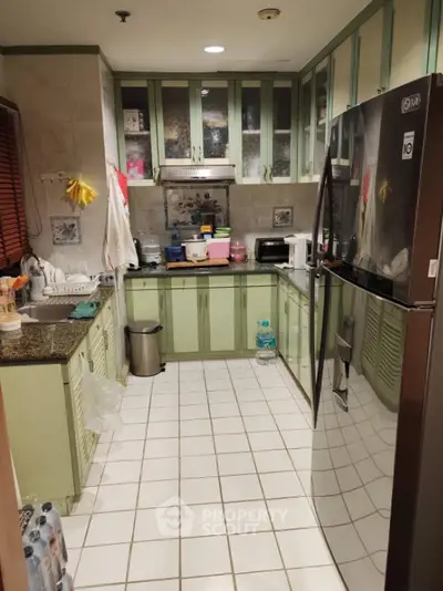 Charming kitchen with green cabinetry and modern appliances in cozy apartment.
