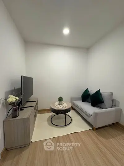 Cozy minimalist living room with modern sofa and TV setup, perfect for relaxation.