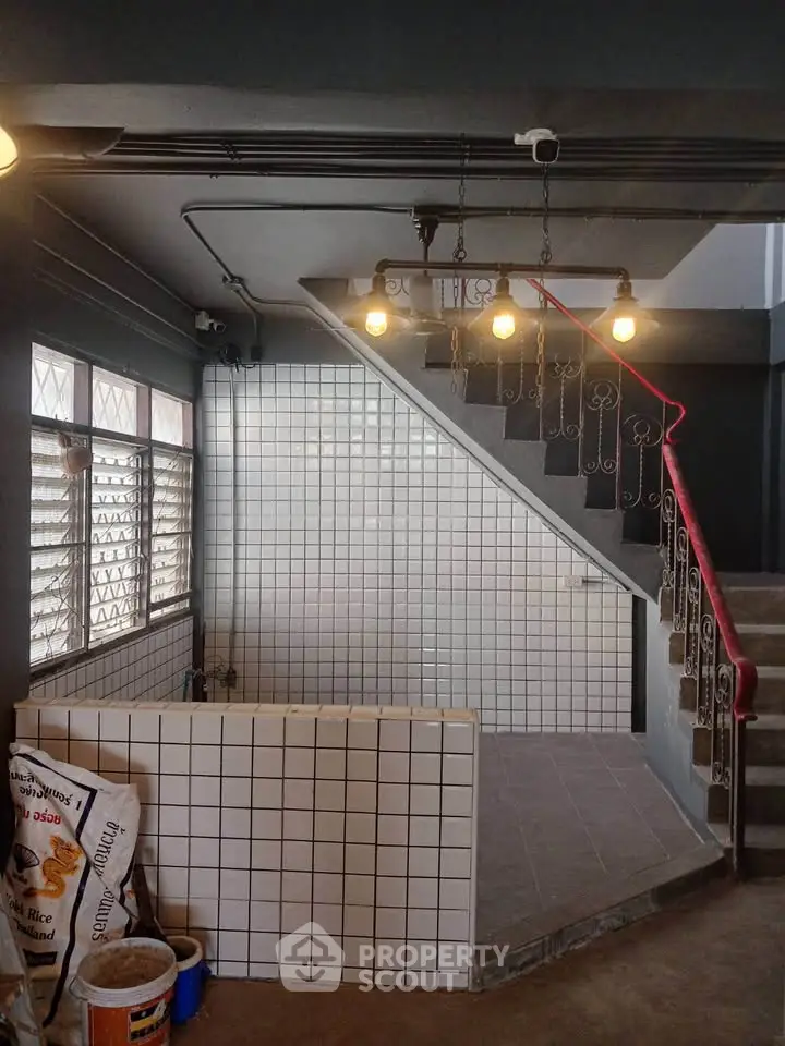 Charming industrial-style staircase with tiled walls and vintage lighting in a modern building.