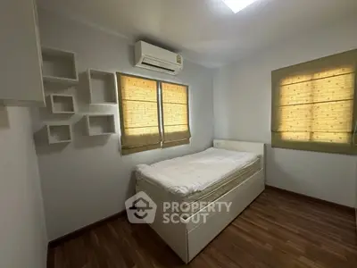 Cozy bedroom with modern design, featuring wooden flooring and air conditioning, perfect for relaxation.