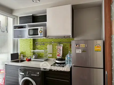 Modern kitchen with green backsplash, stainless steel fridge, and washing machine, ideal for compact living spaces.