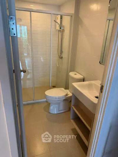 Modern bathroom with glass shower enclosure and sleek fixtures in a contemporary apartment.