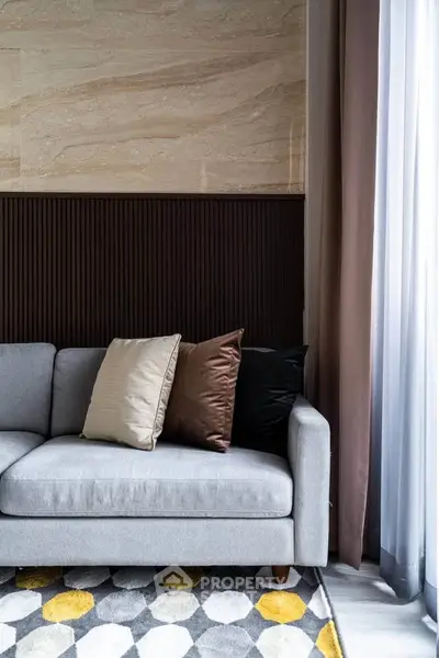 Stylish modern living room with elegant sofa and decorative pillows, featuring a chic geometric rug and natural light.