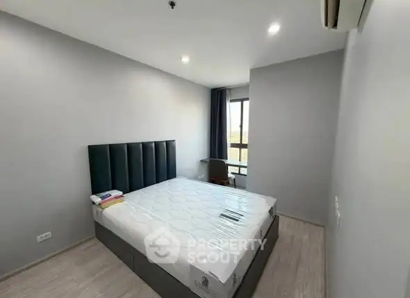 Modern bedroom with minimalist design and large window offering natural light.