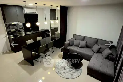 Modern open-layout living room with sleek kitchen, stylish furniture, and elegant lighting.