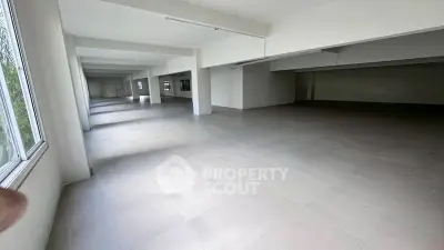 Spacious open-plan interior with large windows and tiled flooring, ideal for versatile use.