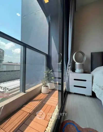 Modern bedroom with floor-to-ceiling windows and small balcony offering city views.