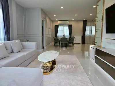 Spacious modern living room with elegant decor and open dining area, featuring sleek furniture and ample natural light.