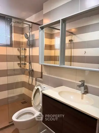 Modern bathroom with glass shower and sleek vanity in contemporary home.