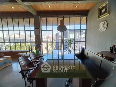 Stylish modern living room with large windows and urban view, featuring elegant furniture and decor.