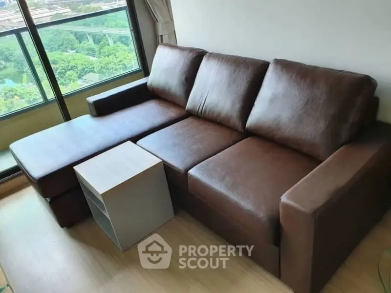 Modern living room with brown leather sofa and scenic balcony view