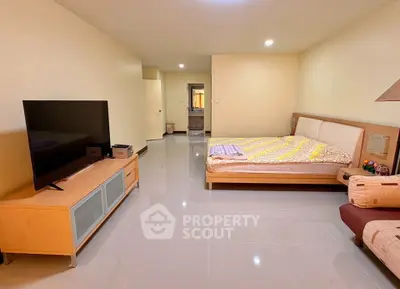 Spacious bedroom with modern furnishings and large TV, perfect for comfortable living.