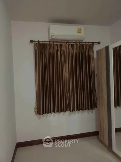 Minimalist bedroom with air conditioning and brown curtains, perfect for cozy living.