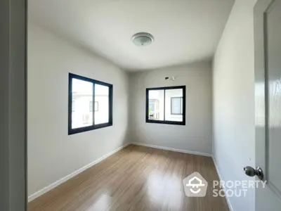 Bright and airy corner unit with gleaming hardwood floors and dual windows offering ample natural light, perfect for a cozy living space.