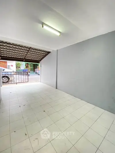 Spacious tiled garage with covered roof and street view, ideal for parking or storage.