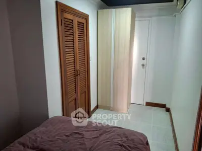 Cozy bedroom with wooden closet and modern wardrobe, perfect for compact living.