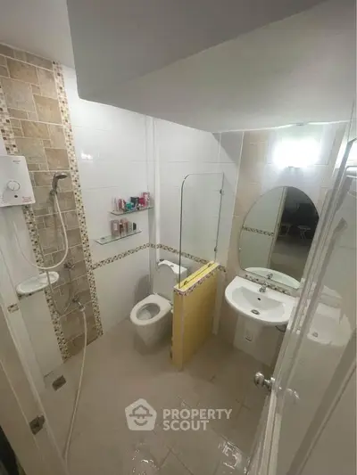 Compact bathroom with modern shower and sleek fixtures in a cozy real estate unit.