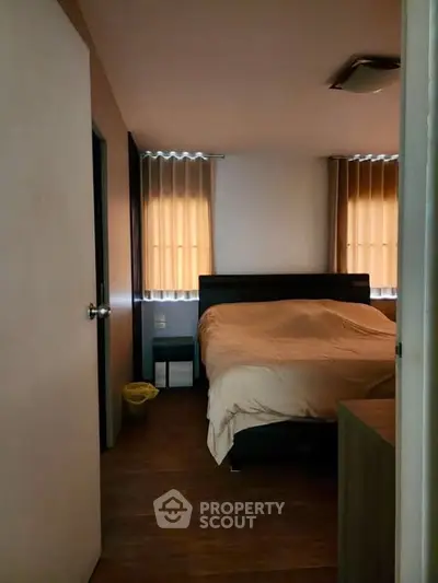 Cozy bedroom with warm lighting and wooden flooring, featuring a comfortable bed and modern decor.