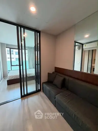 Modern apartment interior with cozy living room and bedroom separated by glass doors, featuring sleek design and ample natural light.