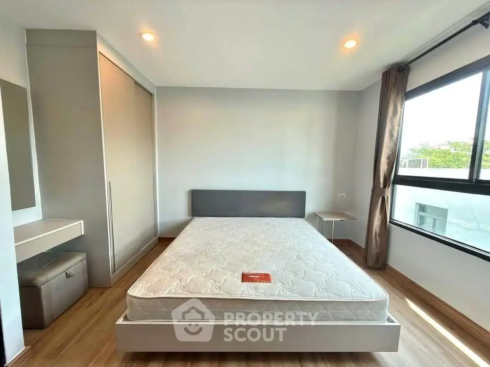 Spacious bedroom with large window and modern furnishings