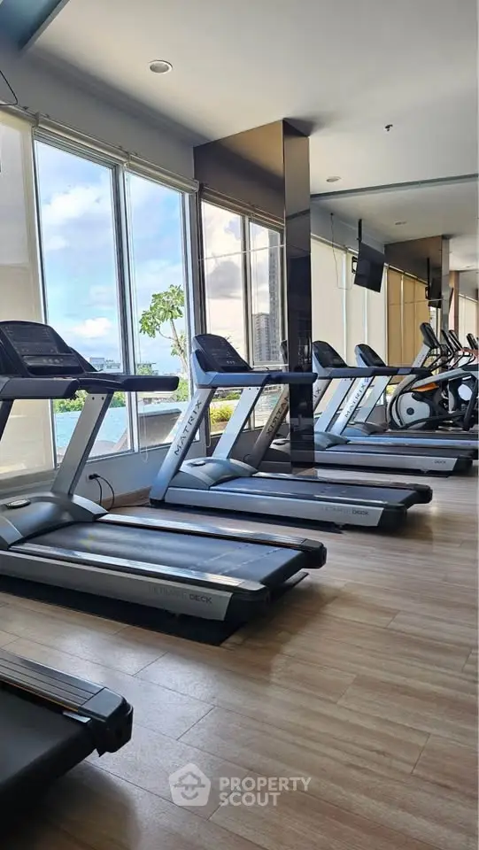Modern gym with treadmills and large windows offering scenic views, perfect for fitness enthusiasts.