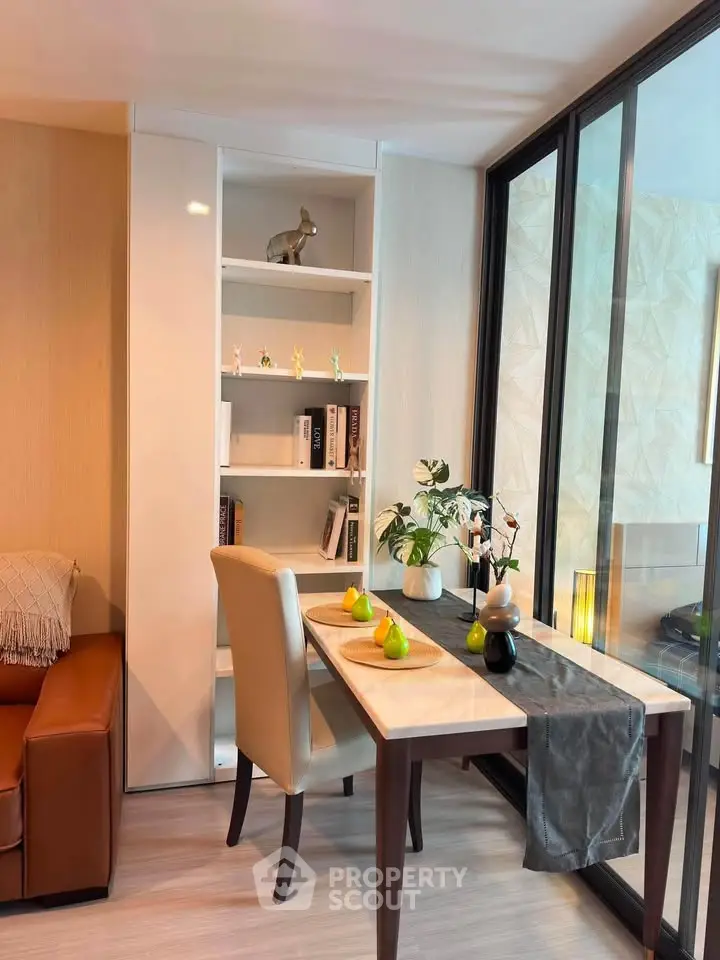 Stylish modern living room with elegant dining table and bookshelf, featuring floor-to-ceiling windows.